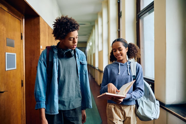 Two youg students compare notes between class.