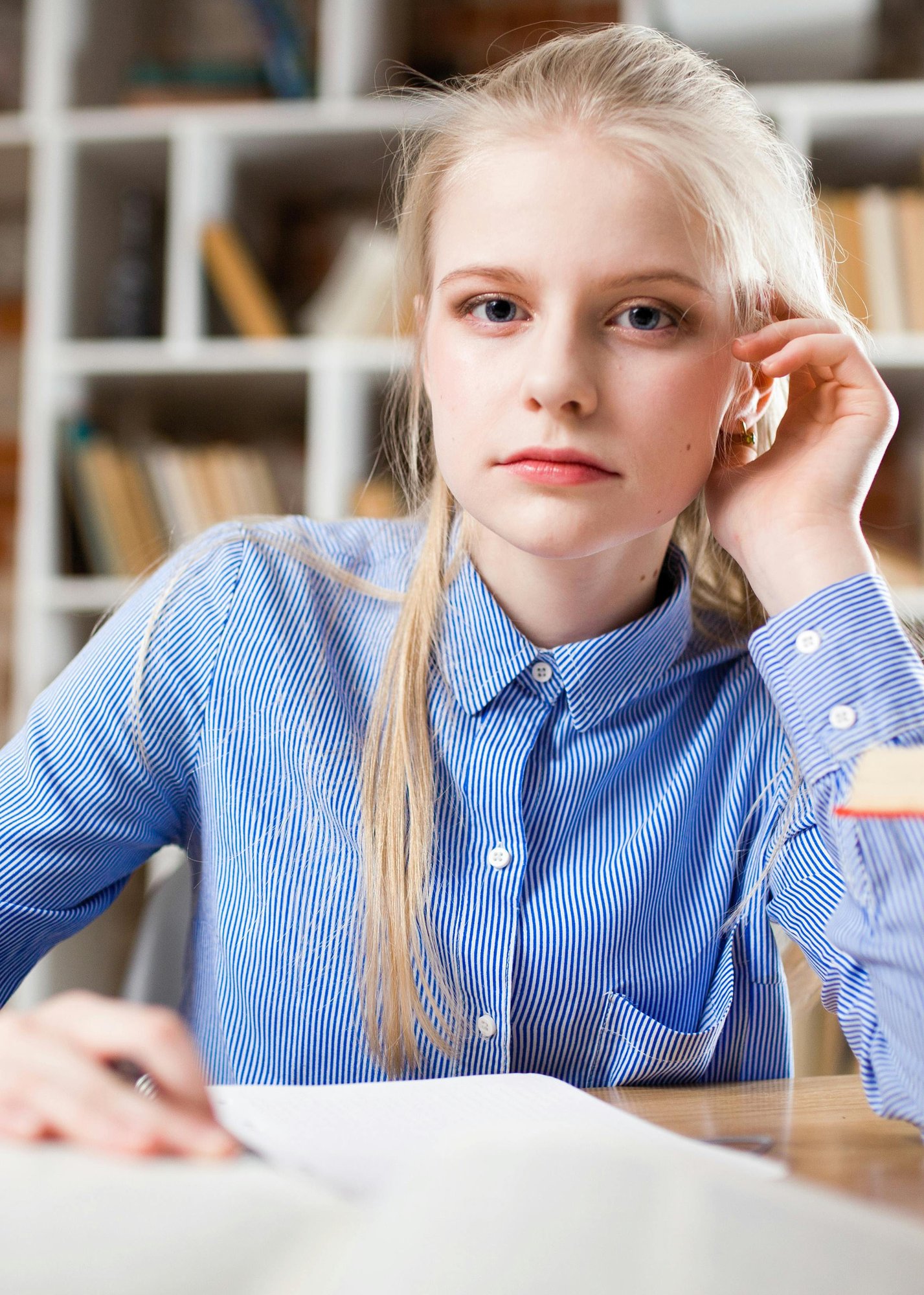 Middle school girl staring intently into camera while studying at school